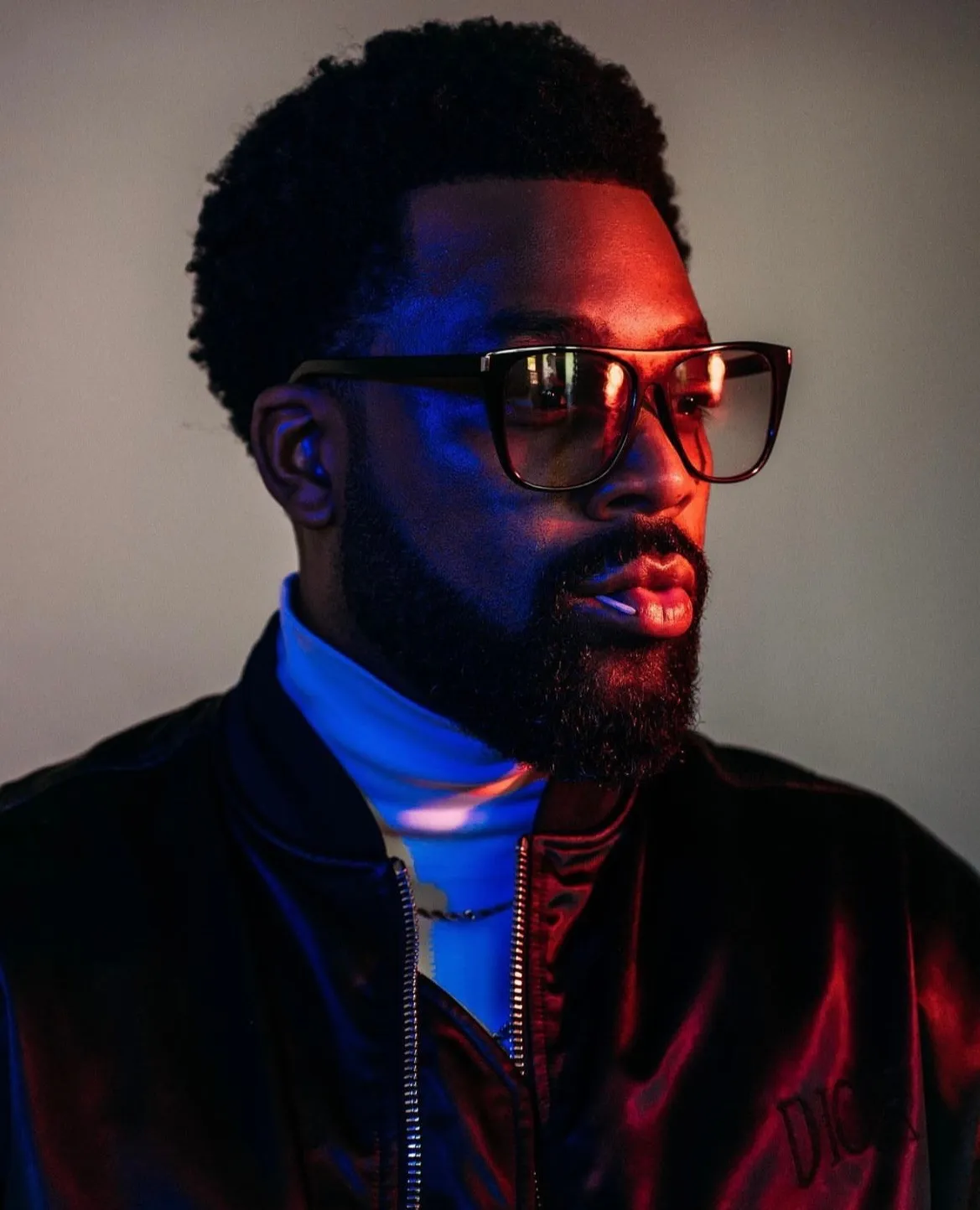 LaRoyce in tinted glasses under red and blue light